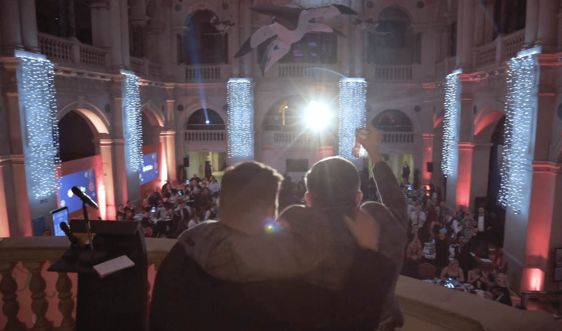 men cheering on balcony at event